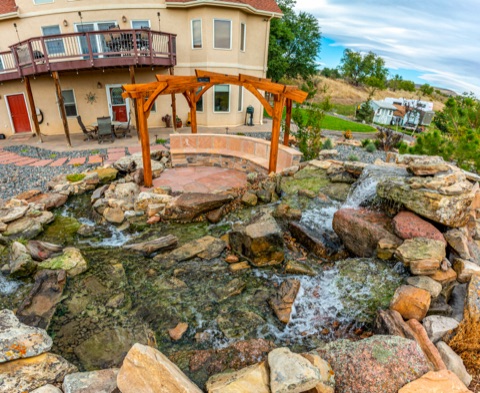 Stream and pergola by a yellow house