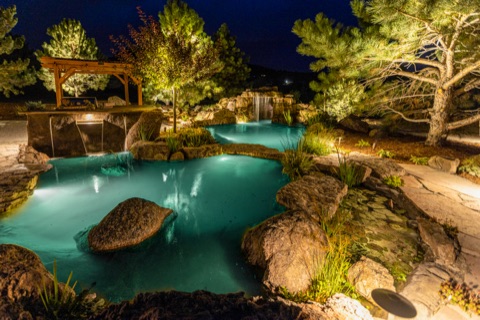Natural pool lit blue at night, trees