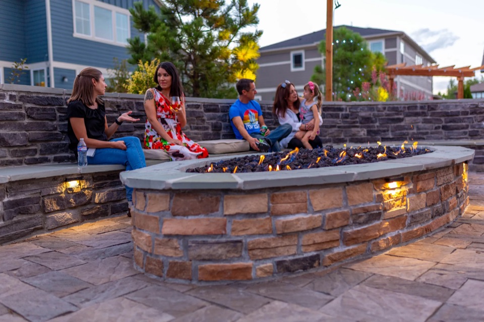 Friends on a seat wall around a fire pit