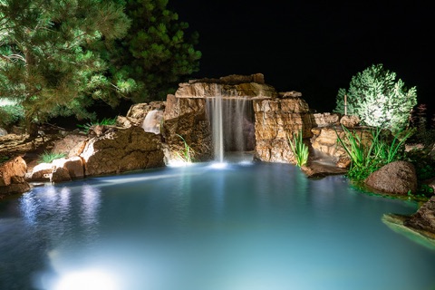 Grotto waterfall into a blue-lit pool at night