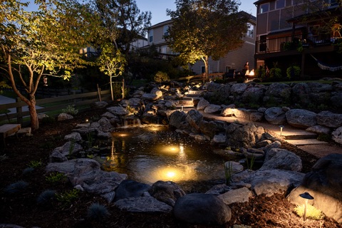 Lit boulders and pond at dusk