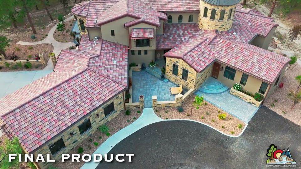 Aerial view of a finished LCM Outdoor Living project: a stone house with a paver courtyard, steps and gravel planting beds