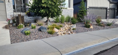 Basalt column fountain and river rock dry creek among boulders, grasses, coneflowers and Russian sage