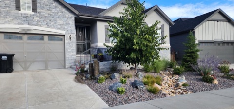 Entry bed with a basalt column fountain, boulders, a river rock dry creek and Russian sage